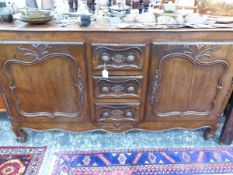 A 19th C. FRENCH PROVINCIAL OAK SIDE BOARD, THE CENTRAL THREE DRAWERS FLANKED BY DOORS WITH CARVED