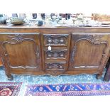 A 19th C. FRENCH PROVINCIAL OAK SIDE BOARD, THE CENTRAL THREE DRAWERS FLANKED BY DOORS WITH CARVED