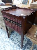 A MAHOGANY NIGHT TABLE WITH HANDLES PIERCED IN THE GALLERIED TOP ABOVE A DOOR WITH A BOOK