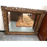 A LATE 19th/EARLY 20th C. RECTANGULAR MIRROR WITHIN A GILT FRAME PIERCED WITH FOLIAGE. 96 x 116cms.