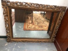 A LATE 19th/EARLY 20th C. RECTANGULAR MIRROR WITHIN A GILT FRAME PIERCED WITH FOLIAGE. 96 x 116cms.