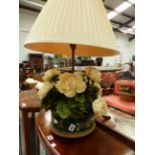 AN UNUSUAL TABLE LAMP WITH FAUX FLOWER AND TOLE BASE.