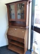 AN EDWARDIAN OAK ARTS AND CRAFTS STYLE SECRETARY BOOKCASE, LEADED GLAZED UPPER SECTION ABOVE FALL