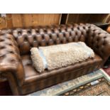 A BUTTON UPHOLSTERED BROWN CHESTERFIELD SETTEE. W 197cms.