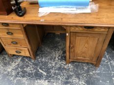 A PINE DESK WITH THE KNEEHOLE FLANKED ON ONE SIDE WITH FOUR DRAWERS AND ON THE OTHER BY A DRAWER