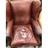 A BROWN LEATHER UPHOLSTERED WING ARMCHAIR ON MAHOGANY CABRIOLE FRONT LEGS