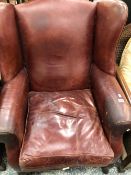 A BROWN LEATHER UPHOLSTERED WING ARMCHAIR ON MAHOGANY CABRIOLE FRONT LEGS