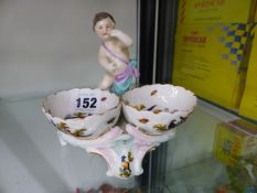 A BERLIN PORCELAIN DOUBLE SALT PAINTED WITH BIRDS AND SURMOUNTED BY A PUTTO
