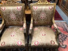 A PAIR OF GILT WOOD ELBOW CHAIRS, THE BACKS UPHOLSTERED WITHIN WAVY BANDS, THE ARM FRONTS CARVED