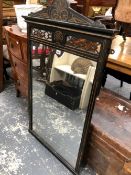 A VICTORIAN RECTANGULAR MIRROR WITHIN AN EBONISED FRAME, THE INCISED FOLIAGE AND ROUNDELS ON THE