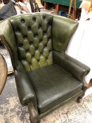 A GREEN LEATHER BUTTON BACKED WING ARM CHAIR ON MAHOGANY CABRIOLE LEGS WITH CLUB FEET.