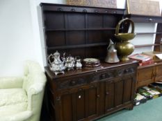 A 20th C. OAK DRESSER, THE ENCLOSED THREE SHELF BACK ABOVE A BASE WITH THREE FOLIATE CARVED