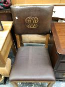 AN ARTS AND CRAFTS OAK CHAIR, THE BROWN LEATHER BACK WITH A GILT LOGO, THE LEATHER SEAT ABOVE SQUARE