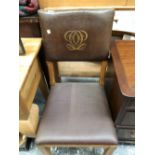 AN ARTS AND CRAFTS OAK CHAIR, THE BROWN LEATHER BACK WITH A GILT LOGO, THE LEATHER SEAT ABOVE SQUARE