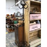 AN IRON COAT STAND WITH THE HOOKS FORMED OF HORSE SHOES, THE SQUARE COLUMN RUNNING DOWN TO HORSE