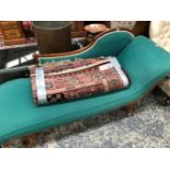 A VICTORIAN MAHOGANY SHOW FRAME CHAISE LONGUE UPHOLSTERED IN GREEN, THE CARVED LEGS SWEEPING DOWN TO