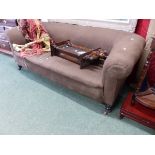 A BROWN UPHOLSTERED CHESTERFIELD ON TURNED MAHOGANY LEGS WITH CERAMIC CASTER FEET. W 190 x D 77 x