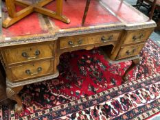 A 20th C. WALNUT FIVE DRAWER WRITING TABLE WITH THREE RED LEATHER INSETS TO THE TOP, THE CABRIOLE