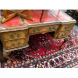 A 20th C. WALNUT FIVE DRAWER WRITING TABLE WITH THREE RED LEATHER INSETS TO THE TOP, THE CABRIOLE