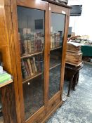 A 20th C. OAK DISPLAY CABINET, THE GLAZED DOORS BETWEEN FLUTED PILASTERS AND ENCLOSING FOUR