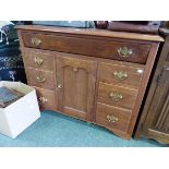 A 20th C. TEAK CHEST WITH THE LIFT UP TOP OVER BANKS OF THREE DRAWERS FLANKINGA CUPBOARD. W 108 x