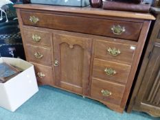 A 20th C. TEAK CHEST WITH THE LIFT UP TOP OVER BANKS OF THREE DRAWERS FLANKINGA CUPBOARD. W 108 x