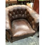 A TUB ARMCHAIR BUTTON UPHOLSTERED IN BROWN LEATHERETTE.