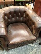 A TUB ARMCHAIR BUTTON UPHOLSTERED IN BROWN LEATHERETTE.