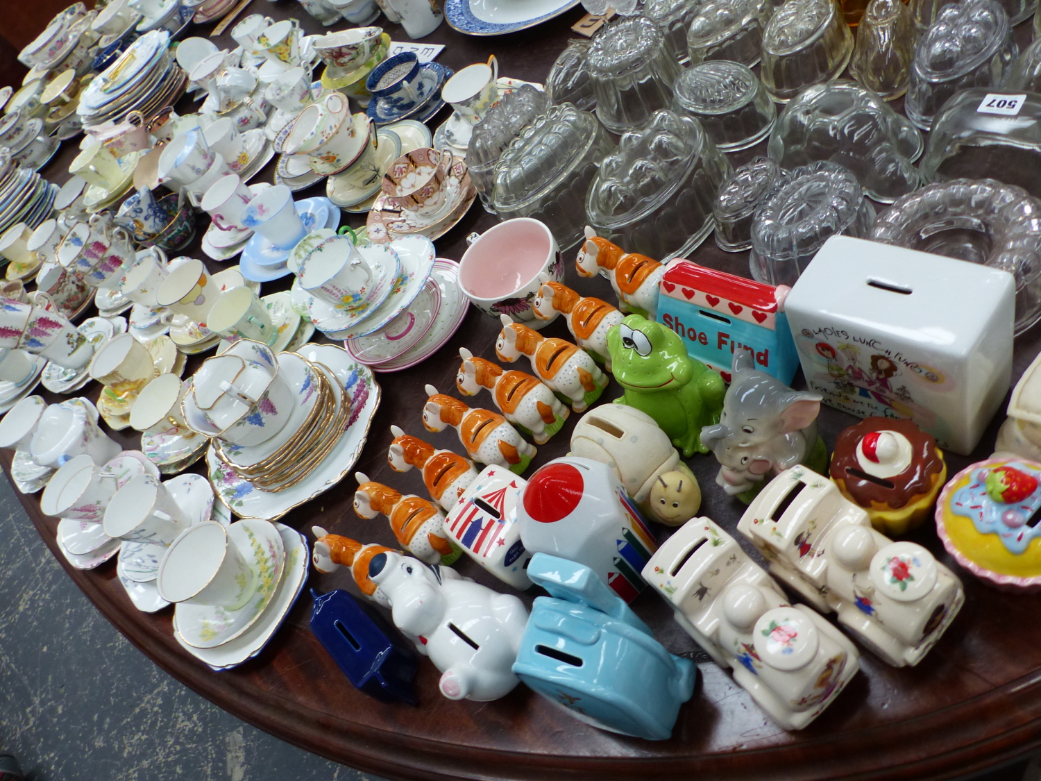 A LARGE COLLECTION OF TEA CUPS, SOUP BOWLS AND SAUCERS TOGETHER WITH GLASS JELLY MOULDS AND MONEY