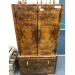 AN ART DECO BURR WALNUT CABINET, THE TWO DOORS OF THE TOP ENCLOSING SHELVES ABOVE TWO DRAWERS AND