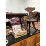 A RUSTIC OAK FOUR LEGGED STOOL TOGETHER WITH AN OAK TRIPOD CHAIR, THE BACK FORMED OF TWO HEARTS ON A
