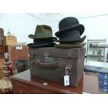 A LEATHER HAT BOX, FOUR TRILBYS AND A BOWLER HAT.