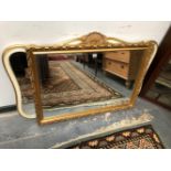 TWO BEVELLED GLASS MIRRORS, ONE IN A RECTANGULAR GILT FRAME, THE LARGER IN A SHAPED RECTANGULAR GILT
