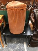 A RED CYLINDRICAL LLOYD LOOM TYPE LINEN BASKET TOGETHER WITH AN EBONISED COFFEE TABLE. W 74 x D 48 x