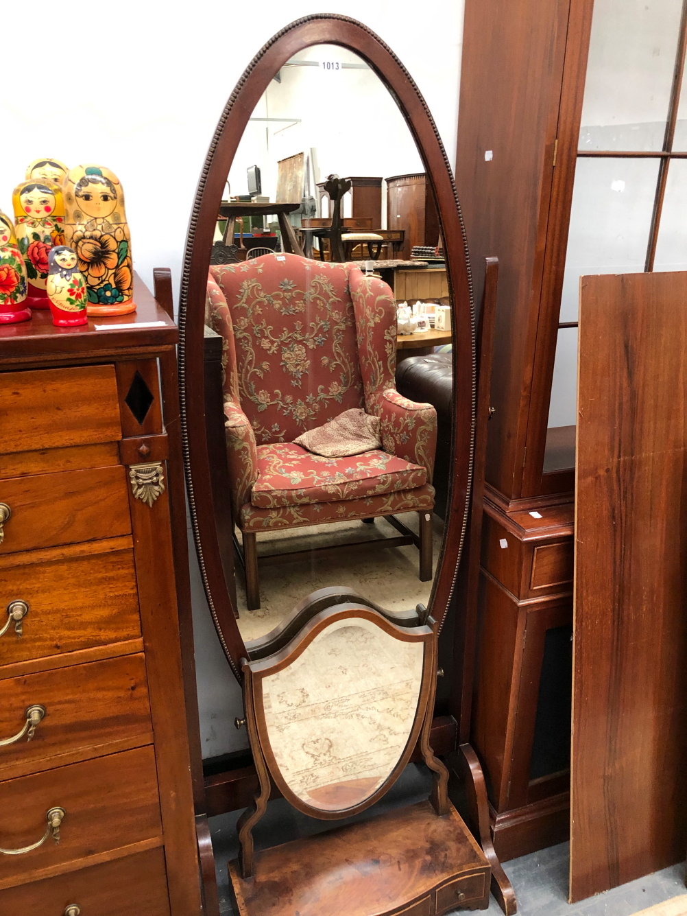 A 20th C. OVAL FULL LENGTH MIRROR IN A MAHOGANY CHEVAL FRAME TOGETHER WITH A GEORGE III SHIELD