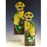 A PAIR OF CHINESE BUDDHIST LIONS SEATED ON RECTANGULAR PLINTHS AND GLAZED IN YELLOW, AUBERGINE AND