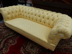 AN EARLY 20th C. CHESTERFIELD BUTTON UPHOLSTERED IN YELLOW DAMASK, THE TURNED MAHOGANY LEGS ON