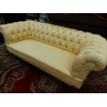 AN EARLY 20th C. CHESTERFIELD BUTTON UPHOLSTERED IN YELLOW DAMASK, THE TURNED MAHOGANY LEGS ON