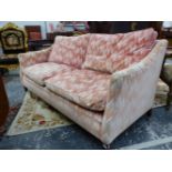 A HOWARD SETTEE WITH UPHOLSTERED RECTANGULAR BACK AND SLOPING ARMS, THE SQUARE MAHOGANY LEGS