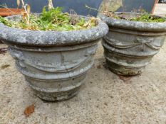 A PAIR OF WEATHERED RECONSTITUTED STONE GARDEN URNS