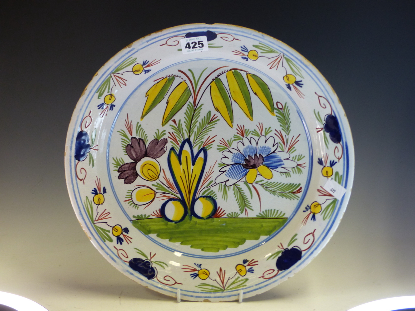 A DUTCH DELFT POLYCHROME DISH, THE CENTRAL EXPLOSION OF FLOWERS ENCLOSED BY A RIM BAND OF BLUE