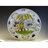 A DUTCH DELFT POLYCHROME DISH, THE CENTRAL EXPLOSION OF FLOWERS ENCLOSED BY A RIM BAND OF BLUE