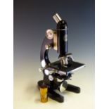 A CASED BAKER OF LONDON MONOCULAR MICROSCOPE WITH THREE LENSES ROTATING OVER THE STAGE WITH A