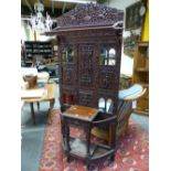 A BURMESE TEAK HALL STAND, THE PANELLED BACK CARVED WITH FIGURES AND FOLIAGE. W 92 x D 37 x H 220c