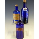 THREE BLUE GLASS PHARMACY BOTTLES AND ONE GLASS STOPPER, ONE LABELLED IN BLACK ON A GILT GROUND HYD.