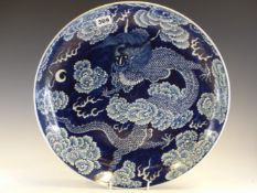A CHINESE BLUE AND WHITE DISH, THE DRAGON AMONGST CLOUDS PICKED OUT IN WHITE AGAINST THE BLUE