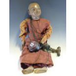 A BURMESE PUPPET DRESSED AS A BUDDHIST MONK WITH A BOWL IN ONE HAND. H 62cms.