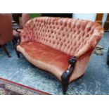 A MAHOGANY THREE SEAT SETTEE BUTTON UPHOLSTERED IN TERRACOTTA VELVET, THE ARM FRONTS CARVED WITH SNA