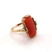 AN ART DECO CORAL TABLET PANEL RING WITH SCROLL SHOULDERS, UNHALLMARKED, STAMPED TO OUTER OF SHANK