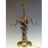 A PARCEL GILT BRONZE TABLE LAMP, THE TWO CHILDREN HOLDING UP AN URN WITH S-SHAPED SNAKE HANDLES AS